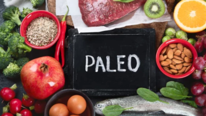 구석기 다이어트(Paleo Diet)란? 식단 원칙, 다이어트 효과, 건강 이점과 부작용에 대한 글의 이해를 돕기 위한 이미지 : 이 이미지에는 신선한 야채, 과일, 견과류, 육류, 생선, 그리고 계란이 테이블에 놓여 있으며, 중앙에 'PALEO'라는 글자가 쓰인 작은 칠판이 놓여 있습니다.